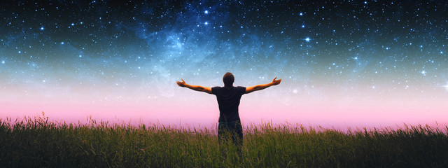 man with arms wide open standing on the grass field against the night starry sky. elements of this i