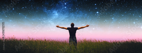 Fotomural Man with arms wide open standing on the grass field against the night starry sky