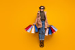 © deagreez - Full body photo of pretty funny lady jumping high up shopping center hold packs wear sun specs casual pink coat pullover jeans leopard print shoes isolated yellow color background