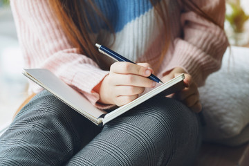 Wall Mural - young woman writing notes on notebook with pen