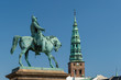 Copenhagen / Denmark 07.03.2015.Statue of King Frederick VII on horseback, and view of the Spire of ancient St. Nicholas church, now St Nicolaj Kunsthal