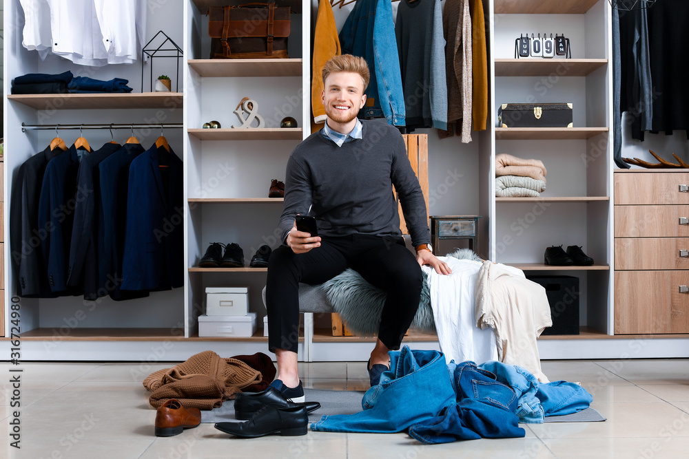 Handsome man choosing clothes in dressing room