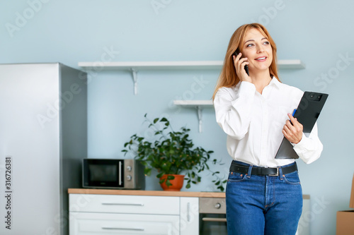 Fotografía Female real estate agent talking by mobile phone indoors