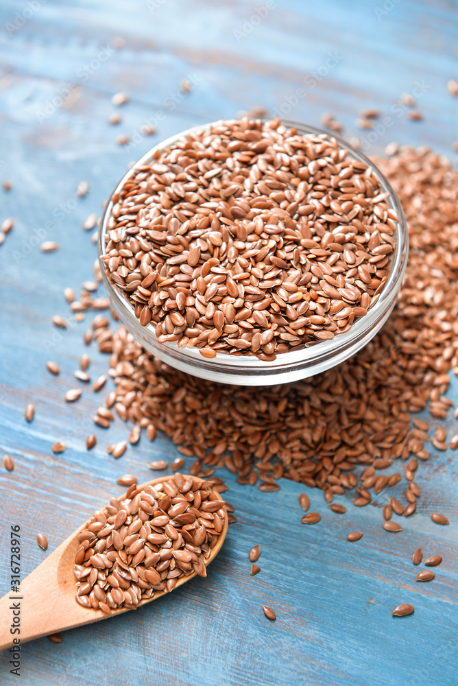 Bowl with flax seeds and spoon on wooden background