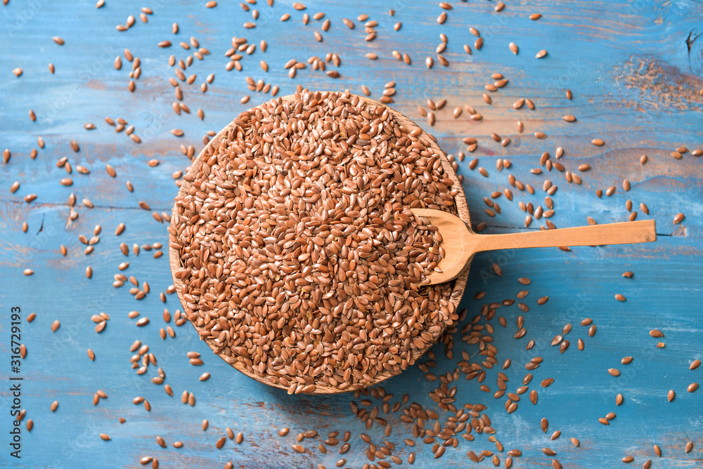 Bowl with flax seeds on wooden background