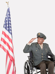 Wall Mural - Senior male US military officer in wheelchair saluting American flag over gray background