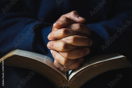 Cuadros en Lienzo Hands folded in prayer on a Holy Bible in church concept for faith