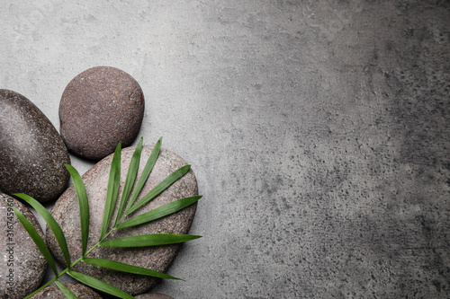 Fotomural Spa stones and palm leaf on grey table, flat lay. Space for text