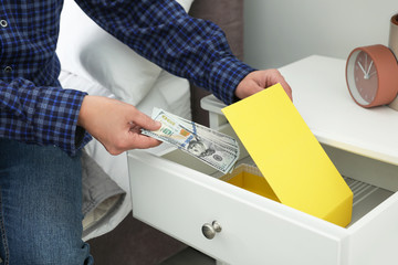 Wall Mural - Man hiding dollar banknotes in cabinet indoors, closeup. Money savings