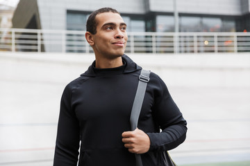 Handsome young smiling sportsman carrying sportsbag