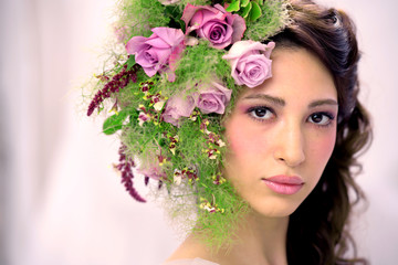 Portrait of beautiful young sexual sensual woman with perfect skin make up curly hair and flowers on head on pink background. Wreath of flowers Spring Summer Fashion Lifestyle People concepts