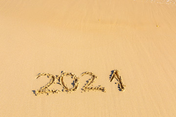 New Year 2021 is coming - inscription 2021 on a beach sand - Summer beach holiday 2021 season golden sand - old year - message handwritten - empty copy space