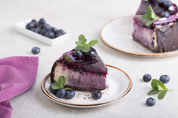 Slice of Blueberry flavour cheesecake swirled with blueberry sauce on a  biscuit crumb, bakery. Delicious slice of blueberries cheesecake with  jam and green mint.  Sweet and tasty food, coffee break 