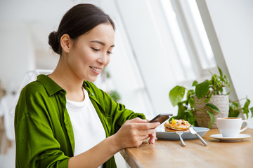 Wall Mural - Smiling asian woman having pancakes for breakfast