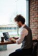 © glazunoff - Attractive bearded young man working on laptop while sitting in