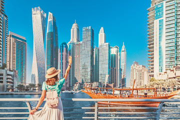 cheerful asian traveler girl walking on a promenade in dubai marina district. travel destinations an