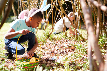 Wall Mural - Group Of Children Wearing Bunny Ears Finding Easter Eggs Hidden In Garden