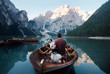 Leinwandbild Motiv man and dog in a boat on a mountain lake. Trip with a pet to Italy. Australian Shepherd Dog and its owner