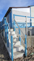 Steps leading from the beach to the cabins by the sea in blue and white.