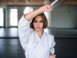 A young woman practising karate indoors in gym.