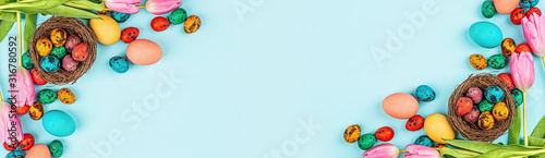Stylish background with colorful easter eggs isolated on blue background with pink tulip flowers Canvas Print