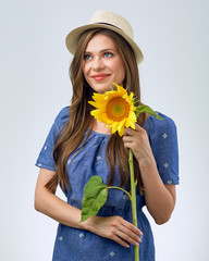 woman holding one sunflower looking away at side.