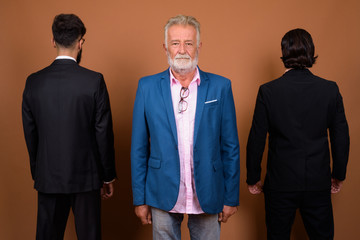 Wall Mural - Three multi ethnic bearded businessmen together against brown background