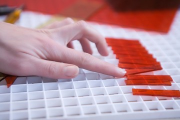 Craftswoman pushes red glass into position