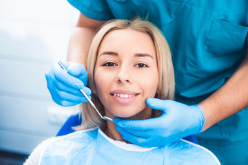 Wall Mural - Dentist examinating blond girl with tools