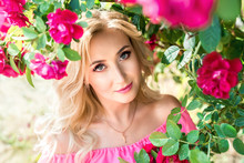 Beautiful Portrait Of A Blonde Girl In Pink Roses. Close-up, Makeup, Extended Eyelashes