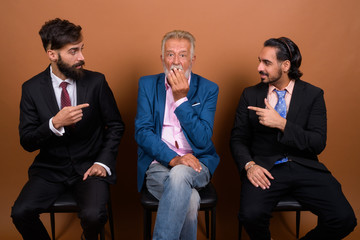 Poster - Three multi ethnic bearded businessmen together against brown background