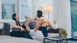 © tirachard - Happy young Asian family play together on couch at home. Chinese mother father and child daughter enjoying happy relax spending time together in modern living room in evening.