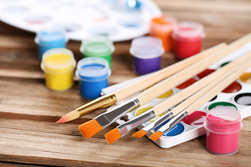 Wall Mural - Colorful gouache paints and brushes on brown wooden table