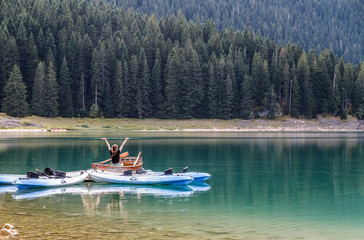 Wall Mural - Black lake in Durmitor national park in Montenegro, boats on the lake reflected in water. Freedom and tranquility.