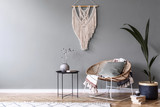Fototapeta Boho - Modern boho interior design of sitting room with design rattan armchair,coffee table, beige macrame, tropical plants and elegant accessories. Stylish home decor.  Template. Copy space. Home staging.