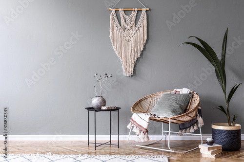 Fotografía Modern boho interior design of sitting room with design rattan armchair,coffee table, beige macrame, tropical plants and elegant accessories