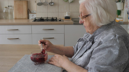 Senior woman is eating dessert - jelly with raspberries