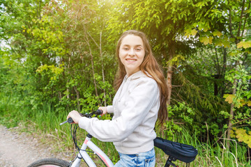 Wall Mural - Young woman riding bicycle in summer city park outdoors. Active people. Hipster girl relax and rider bike. Cycling to work at summer day. Bicycle and ecology lifestyle concept