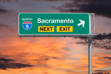 Sacramento California next exit route 5 freeway sign with sunset sky.