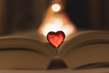 Red Glass Heart On A Book With Bokeh Lights In The Background