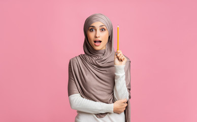 Wall Mural - Inspired muslim girl having idea, holding pencil in raised arm