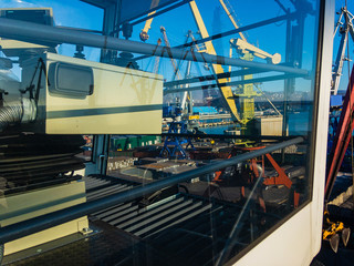 View through the glass cabin of the portal crane on the working area of ​​the port in clear sunny weather.