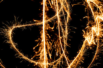 Wall Mural - Abstract pattern of sparks and bright light beams of Golden color on a black background
