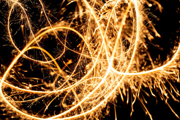 Wall Mural - Abstract pattern of sparks and bright light beams of Golden color on a black background