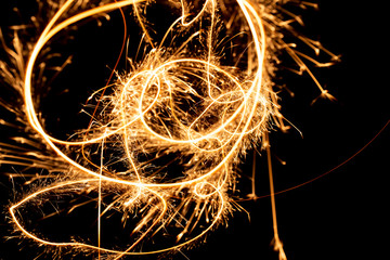 Wall Mural - Abstract pattern of sparks and bright light beams of Golden color on a black background
