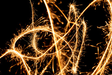 Wall Mural - Abstract pattern of sparks and bright light beams of Golden color on a black background