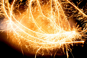 Wall Mural - Abstract pattern of sparks and bright light beams of Golden color on a black background