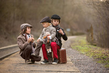 Adorable Boy On A Railway Station, Waiting For The Train With Suitcase And Beautiful Vintage Doll...