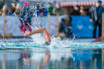 Woman swimming in an outdoor pool at an ice swim competition