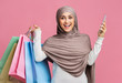 © Prostock-studio - Joyful arabic woman in hijab holding smarphone and bright shopping bags
